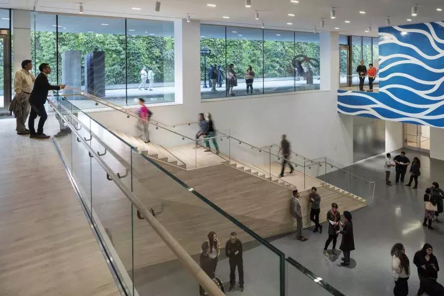 在贝博体彩app现代艺术博物馆的一个简短的房间里，人们从楼梯上下来.